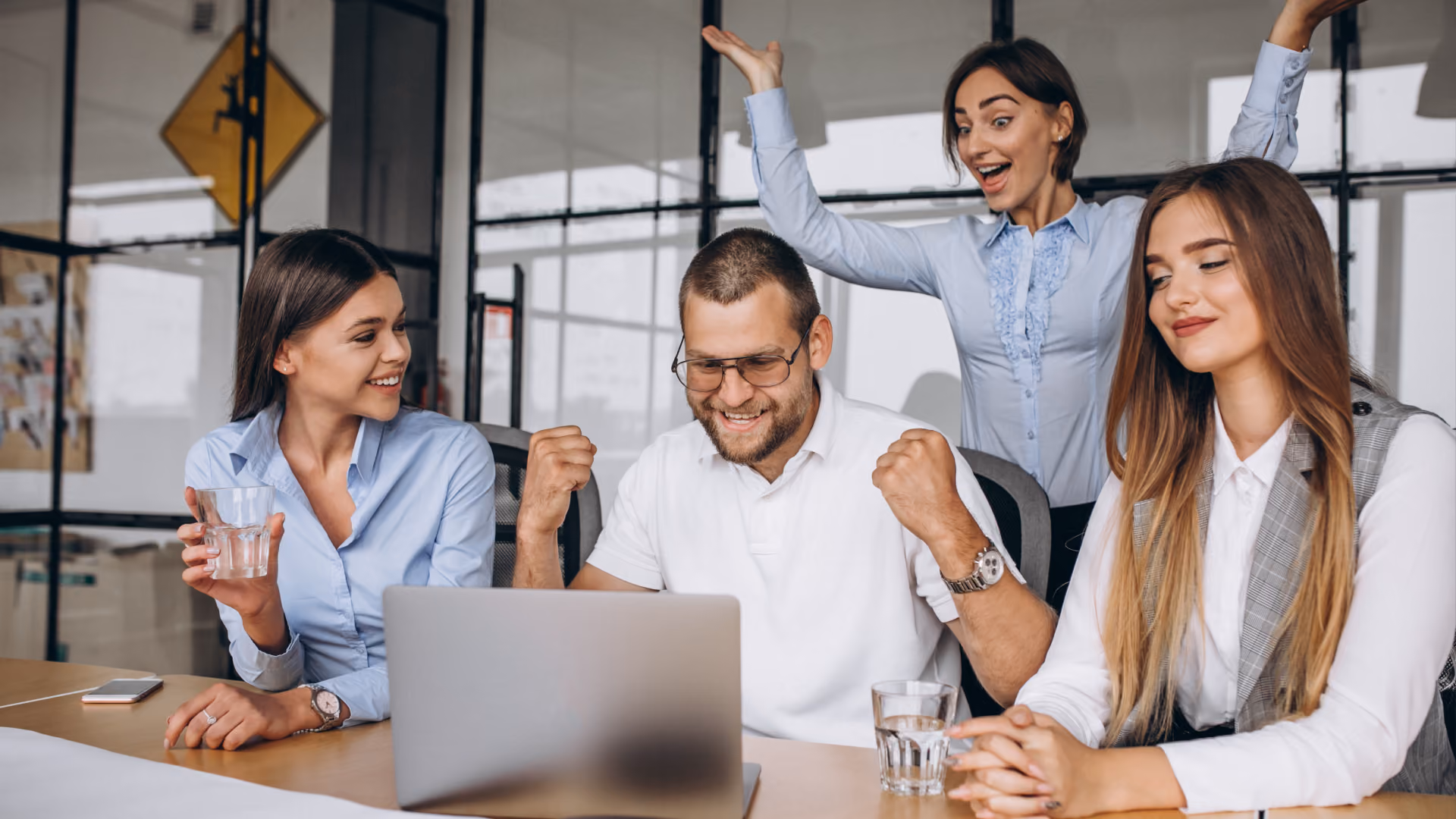 A cheerful team celebrates at a desk, illustrating the positive impact of understanding WFM, WFO, and WEM.