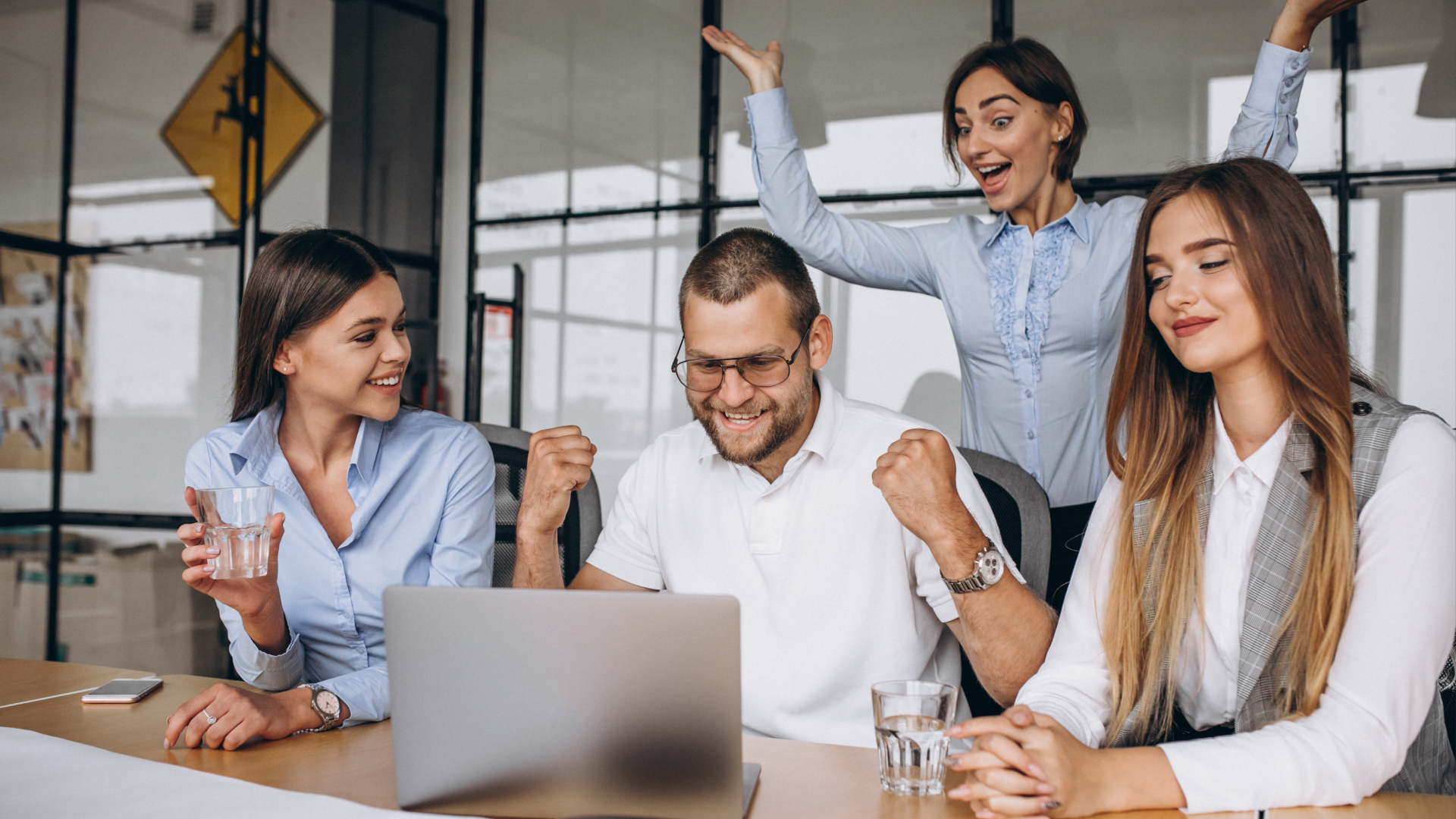 A cheerful team celebrates at a desk, illustrating the positive impact of understanding WFM, WFO, and WEM.
