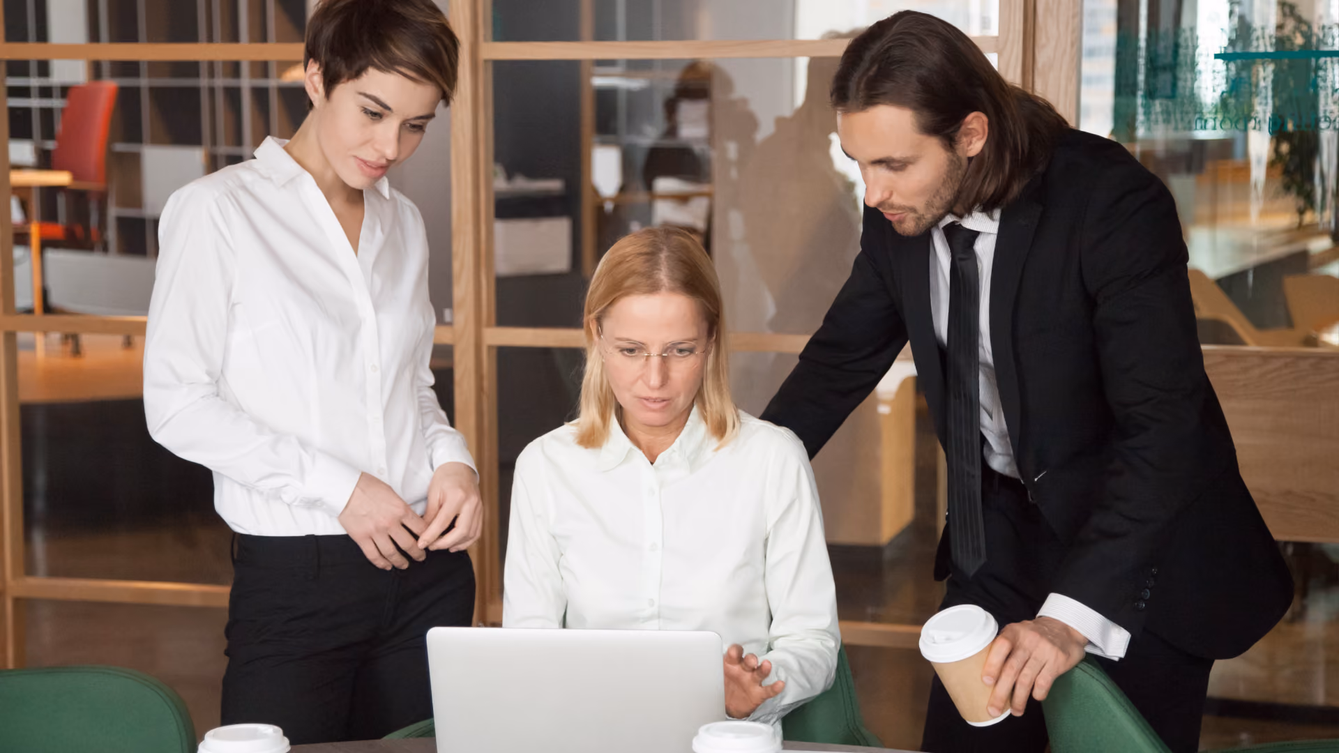 Three professionals collaborate at a desk, focused on building a solid WFM foundation using Synerion software.