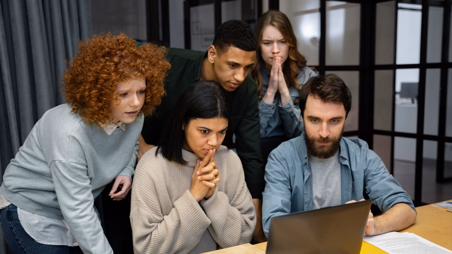 A concerned group huddles around a laptop discussing time clock rules for hourly employees and FLSA requirements.