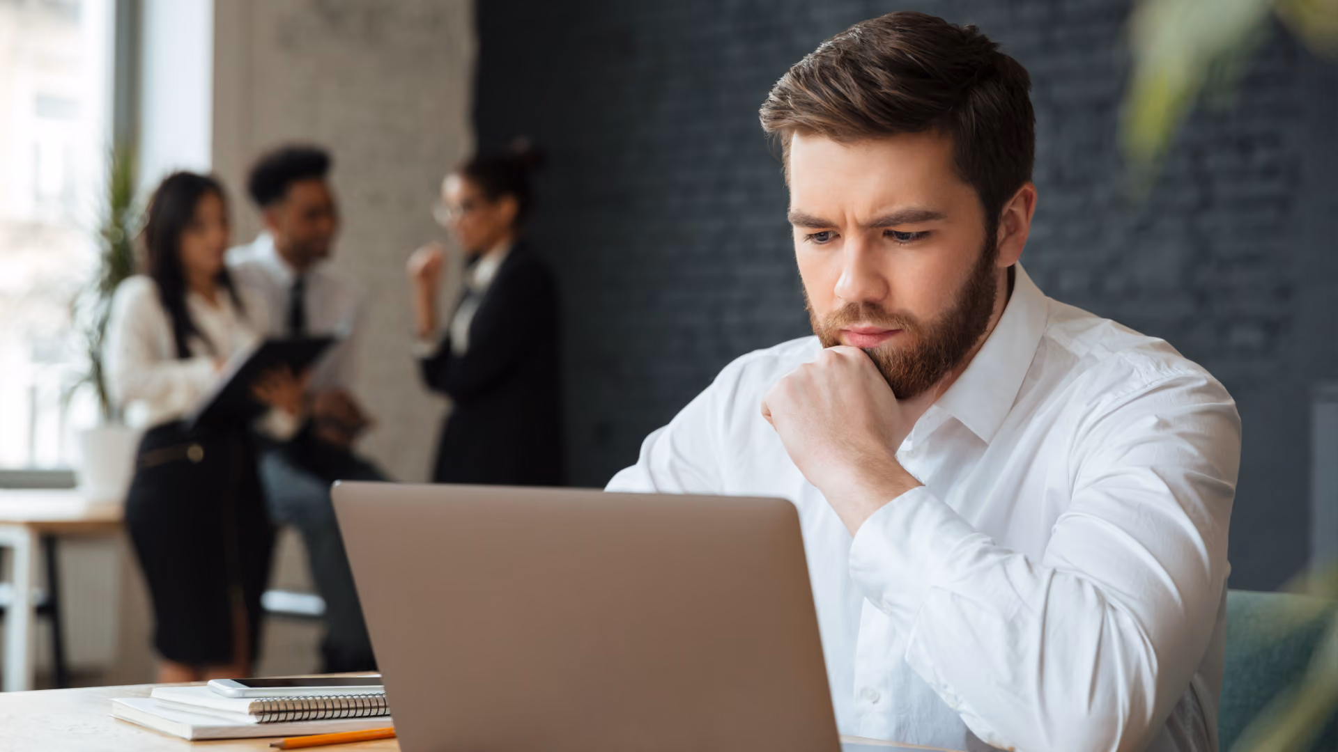 A focused man analyzes a laptop, representing time clock rules for rounding, off-the-clock work, and overtime.