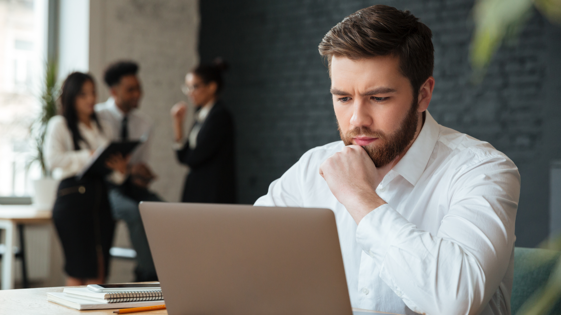 A focused man analyzes a laptop, representing time clock rules for rounding, off-the-clock work, and overtime.