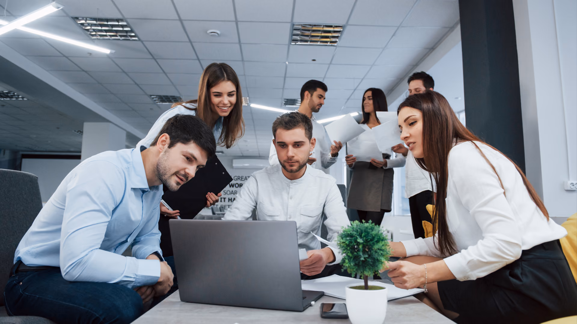 A team collaborates at a laptop to put their time clock compliance strategy into action with Synerion.