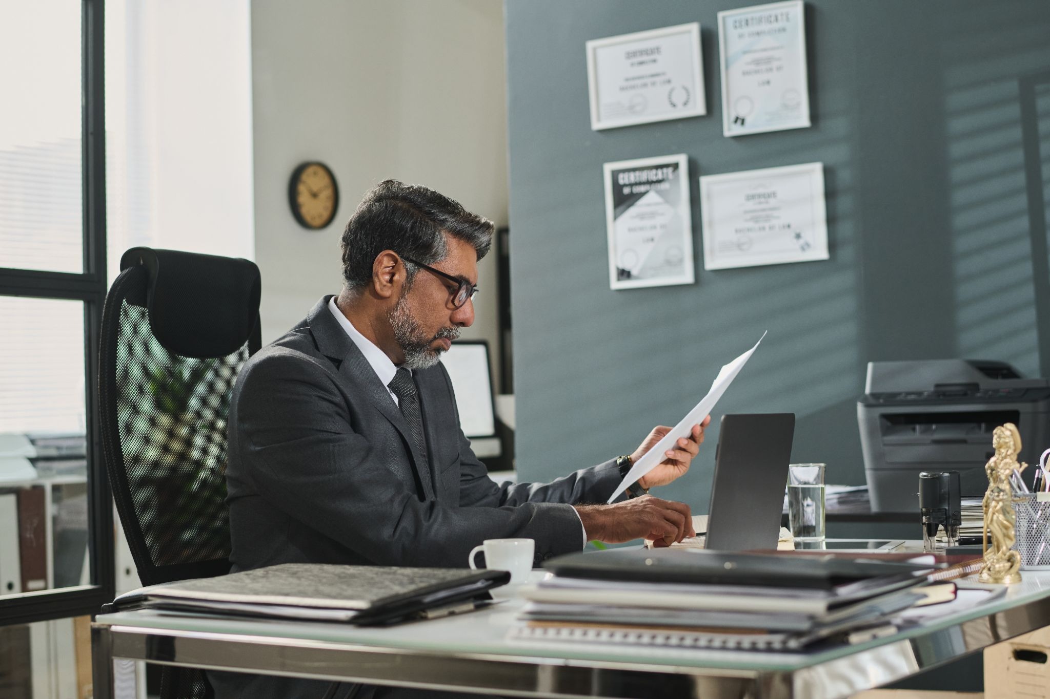 Alt text: Manager in an office reviewing a printed report at his desk.