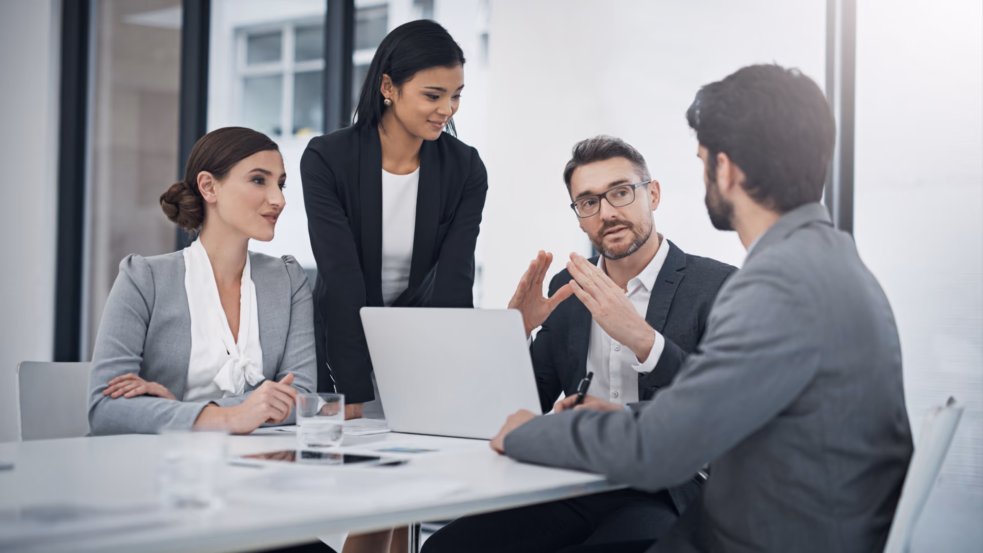 Alt text: Team reviewing performance data on a laptop together during a meeting. 