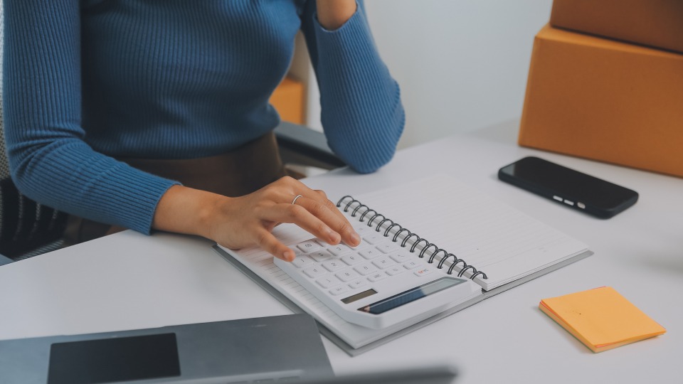A professional uses a calculator and notebook at a desk.