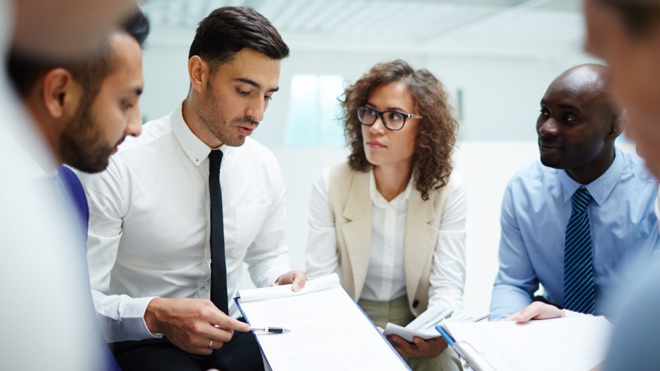 A business team reviews documents during an office meeting.