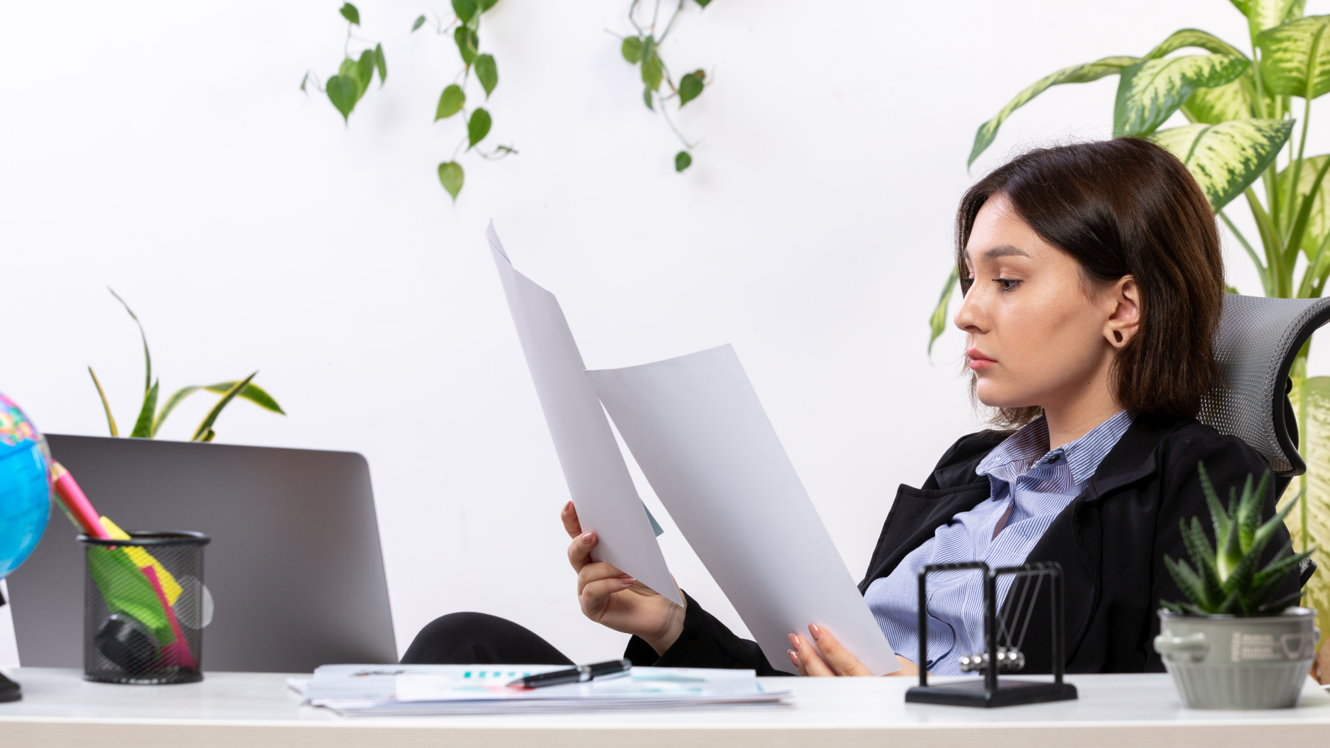 Woman reviewing printed reports at her desk while comparing biometric time clock options.