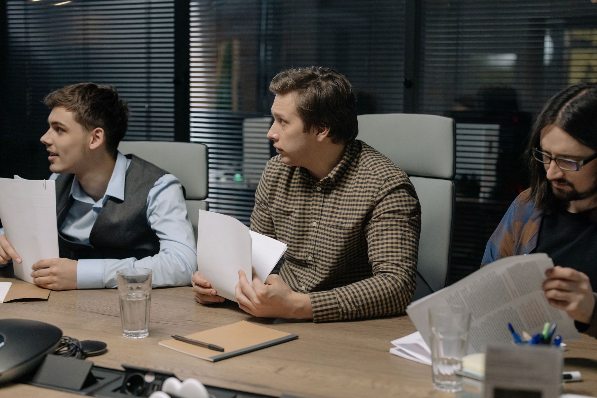 Three colleagues discussing a printed report together at a conference table.