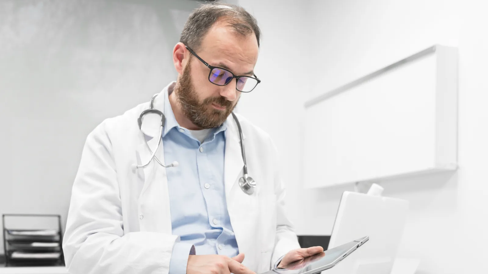 A doctor reviews labor cost data on a tablet to understand what labor cost management includes beyond wages.