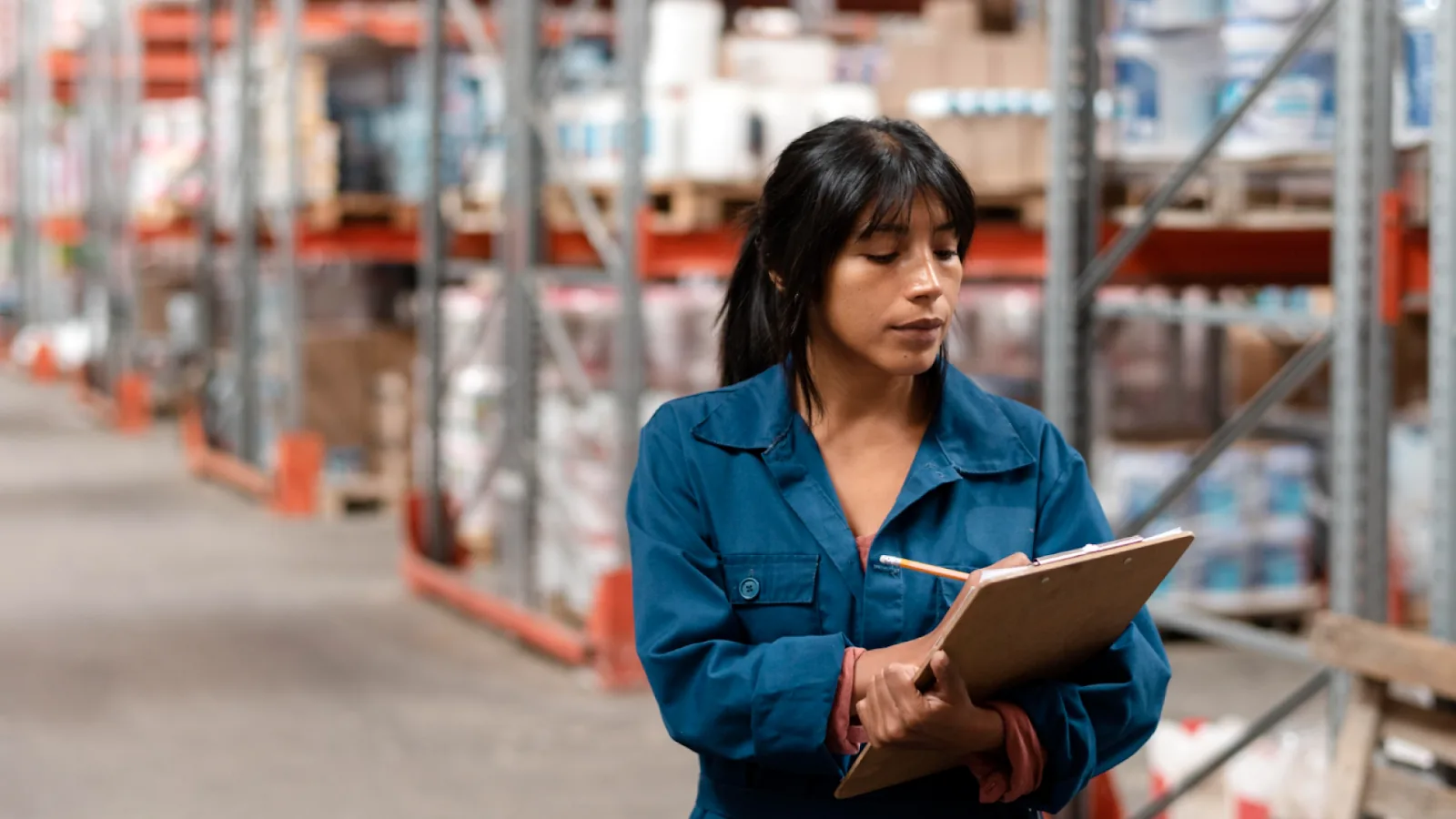 A warehouse worker tracks labor cost metrics on a clipboard to help calculate labor cost and spot cost drift.