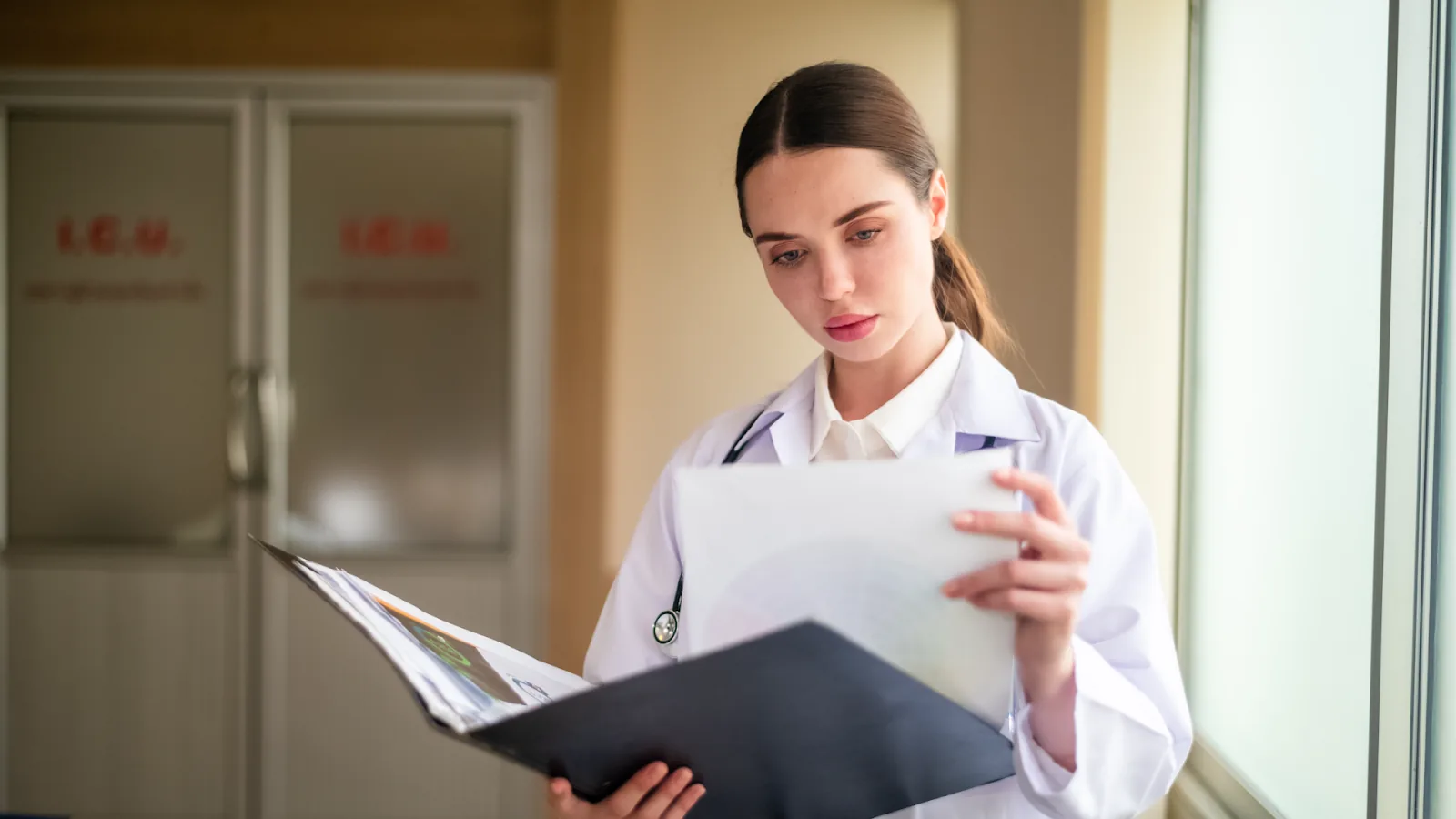 A healthcare worker reviews medical charts to understand causes of absenteeism in the workplace, including illness-related absences.