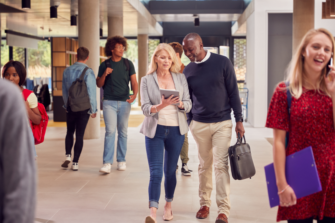 Education benefits leaders discuss employee healthcare strategy while walking through a university campus.