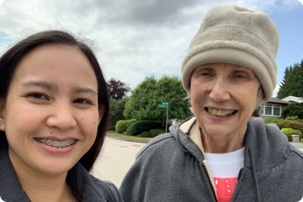 A healthcare worker smiling outside with an elderly client
