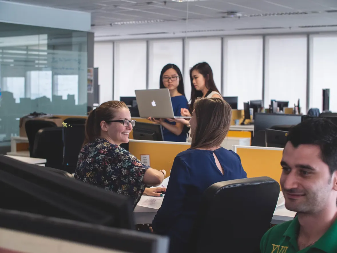 A woman in a blue shirt is sitting at a desk in an office.