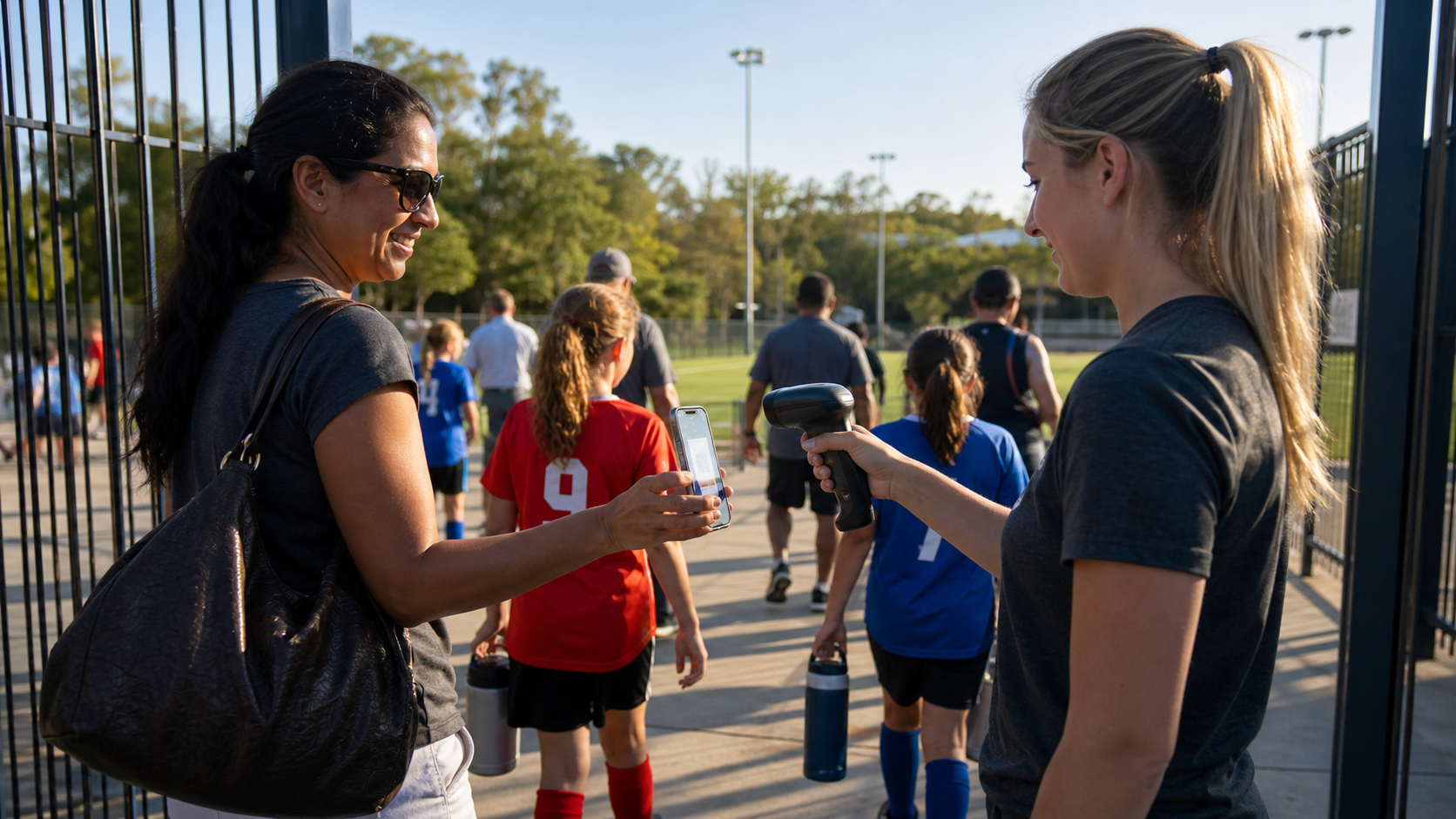 A parent scanning a smartphone at a youth sports event gate entry, a volunteer holding a handheld barcode scanner, bright outdoor sports facility in the background with families arriving, colorful jerseys visible, sunny day atmosphere, realistic photographic style, wide angle view showing the check-in process and crowd energy