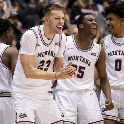 Two University of Montana Men's players wearing their white uniforms.