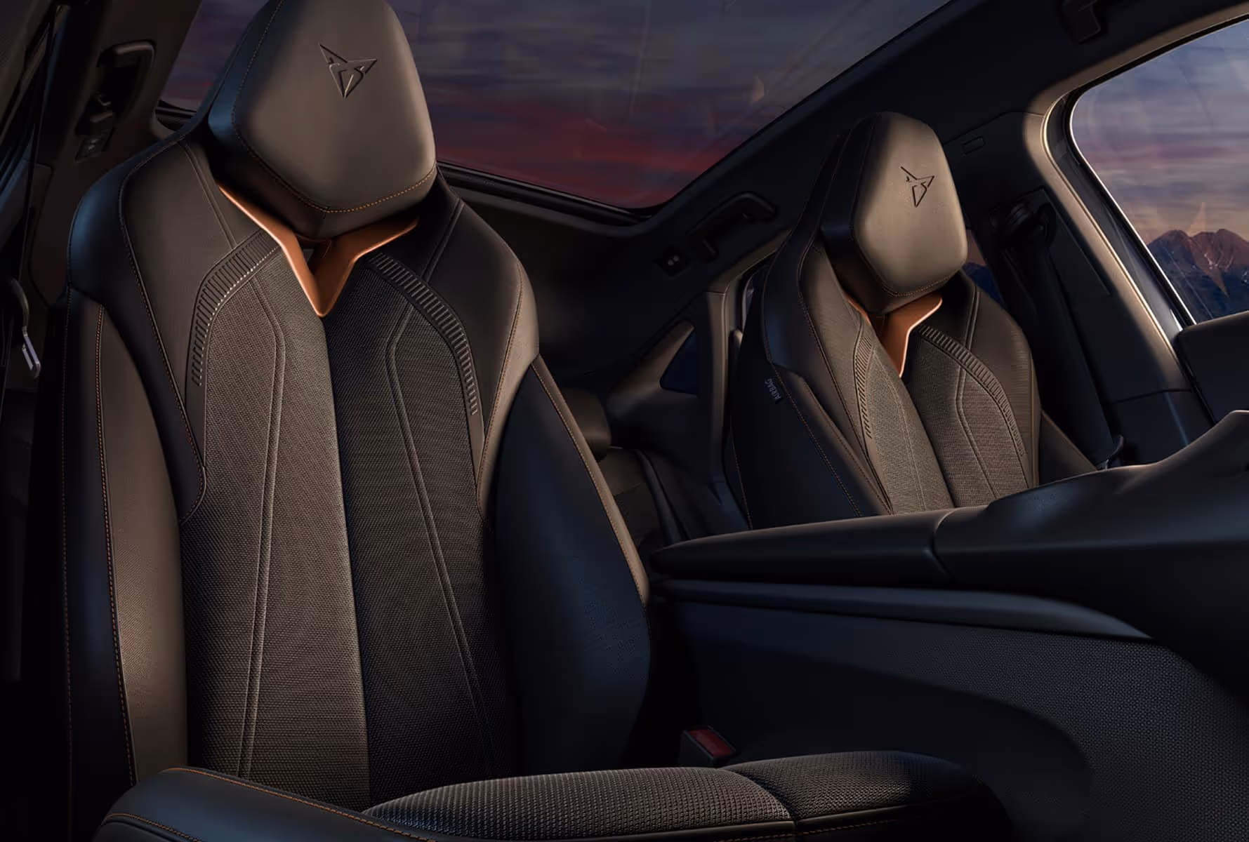Front leather car seats with black and brown accents inside a vehicle, showing detailed stitching and the CUPRA logo on the headrests.