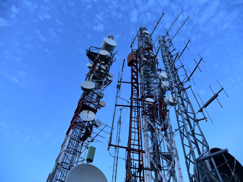 Altas torres de comunicación con varias antenas contra un cielo azul.
