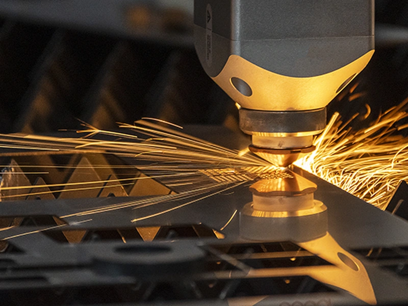 Una máquina de corte por láser que emite chispas brillantes mientras corta una lámina de metal.