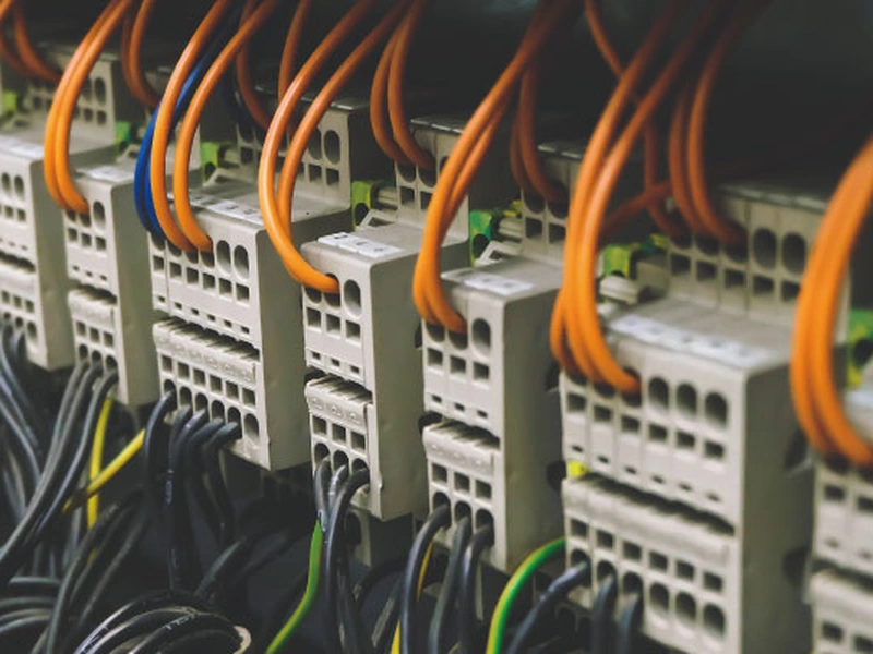 Primer plano de conectores eléctricos industriales con cables naranjas y negros.