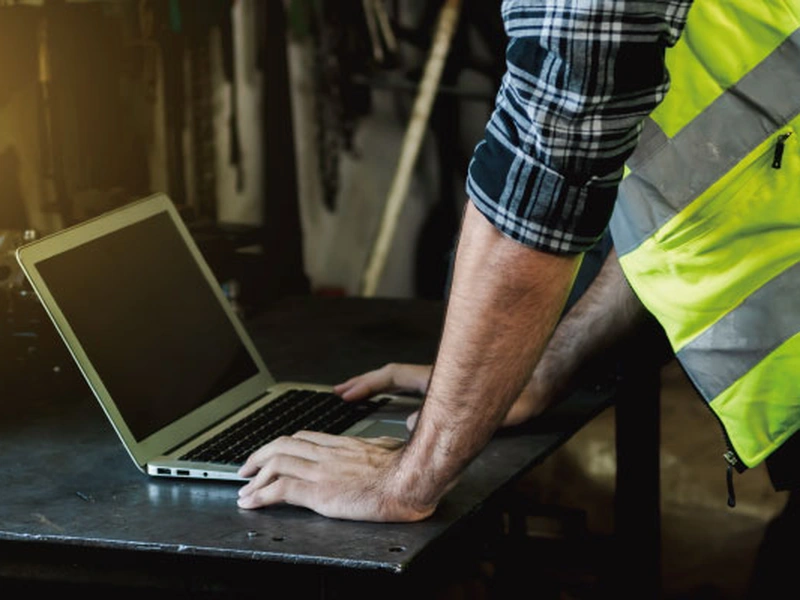 Persona que trabaja en un portátil en un espacio de trabajo industrial.