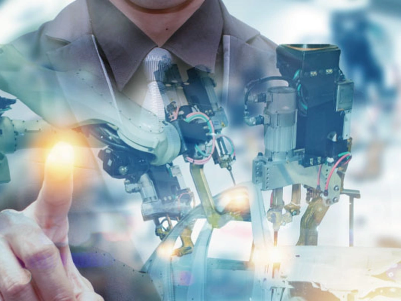 Una persona con un traje toca una interfaz digital brillante, superpuesta con imágenes de maquinaria robótica.