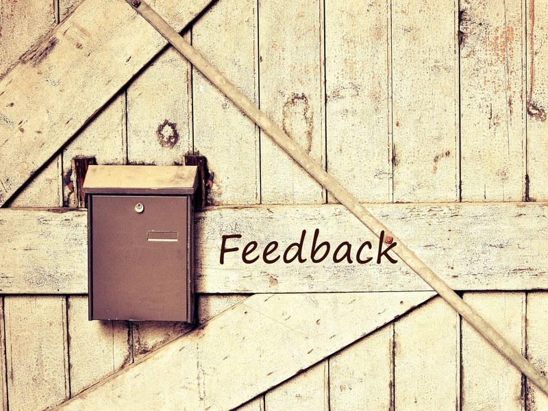 Puerta rústica de madera con un pequeño buzón y la palabra «Feedback» escrita al lado.
