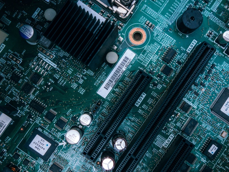 Vista de cerca de la placa base de una computadora con rutas de circuito, ranuras y componentes visibles.