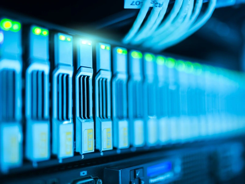 Primer plano de una fila de racks de servidores iluminados con cables conectados en un centro de datos.