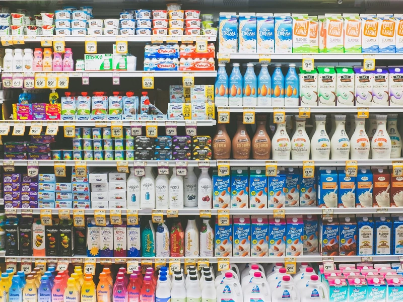 Filas de productos variados de yogur, lácteos y leche no láctea en el pasillo de una tienda de abarrotes.