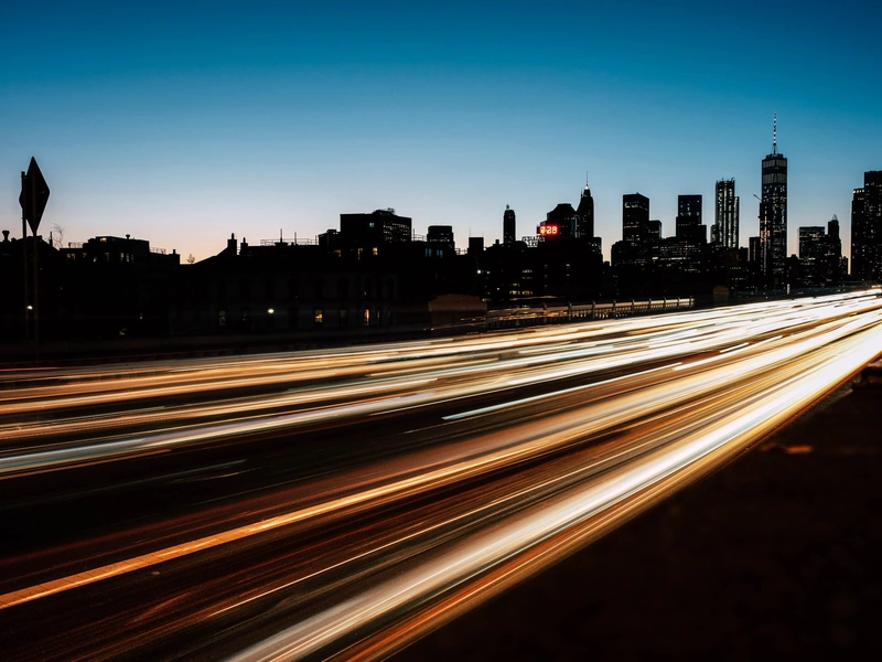 Horizonte de la ciudad al anochecer con rayas de luces de automóviles.