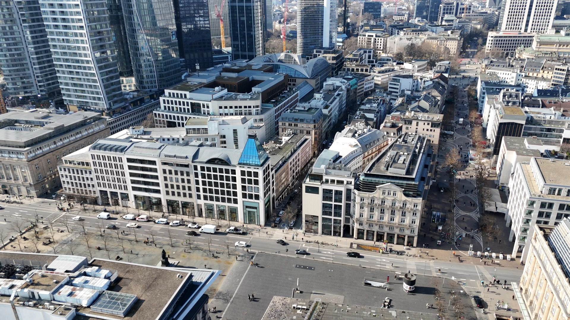 Luftfoto af en travl bydel med moderne og klassiske bygninger, brede gader og mange mennesker.