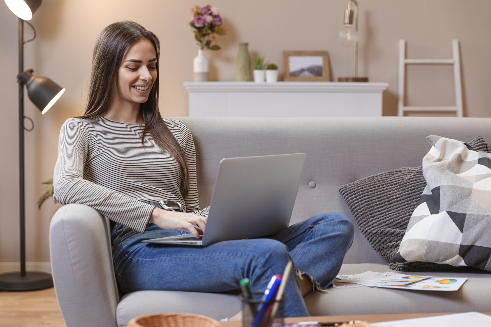 young-woman-working-on-laptop-while-sitting-on-grey-sofa