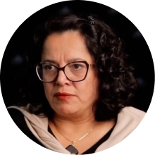 Porträt eines Mannes mit kurzem Haar und weißem Hemd vor dunklem Hintergrund.