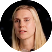 Porträt einer jungen Frau mit langen blonden Haaren vor dunklem Hintergrund.