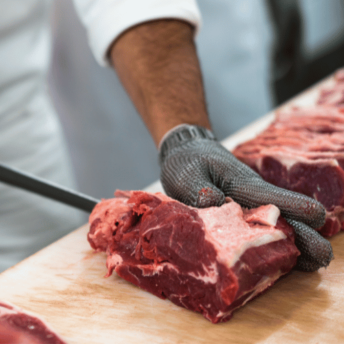 Boucher en intérim découpant de la viande en grande surface pendant une mission