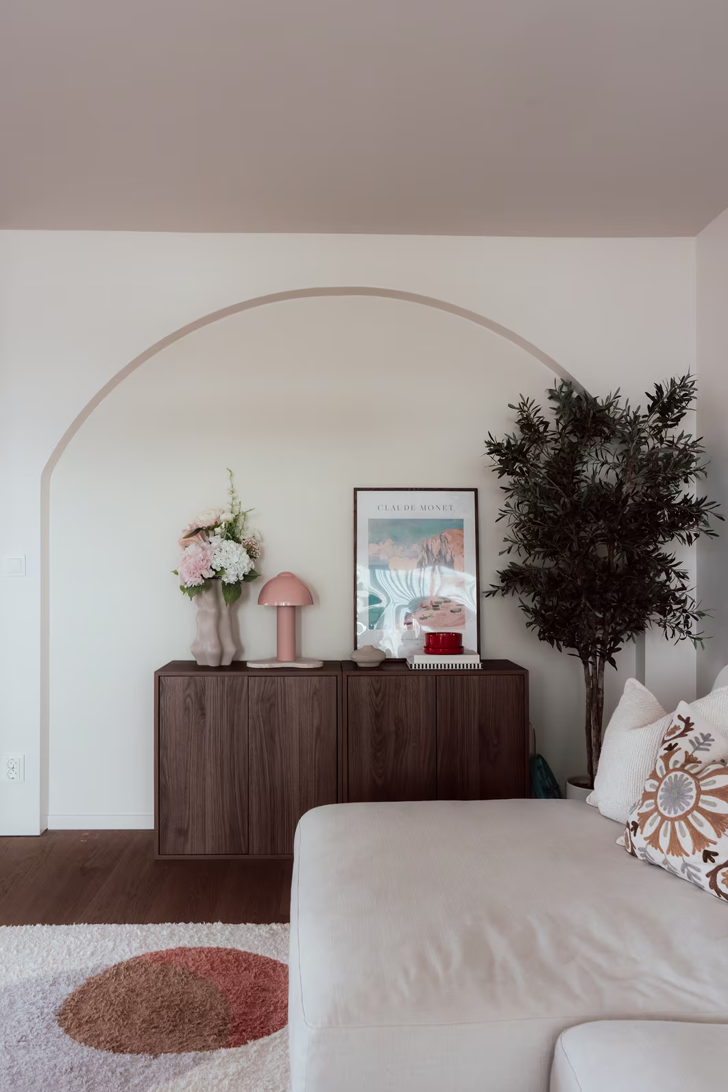 Dekorativ vägg med målat valv och sideboard i mörkt trä, stylat i varm skandinavisk stil.