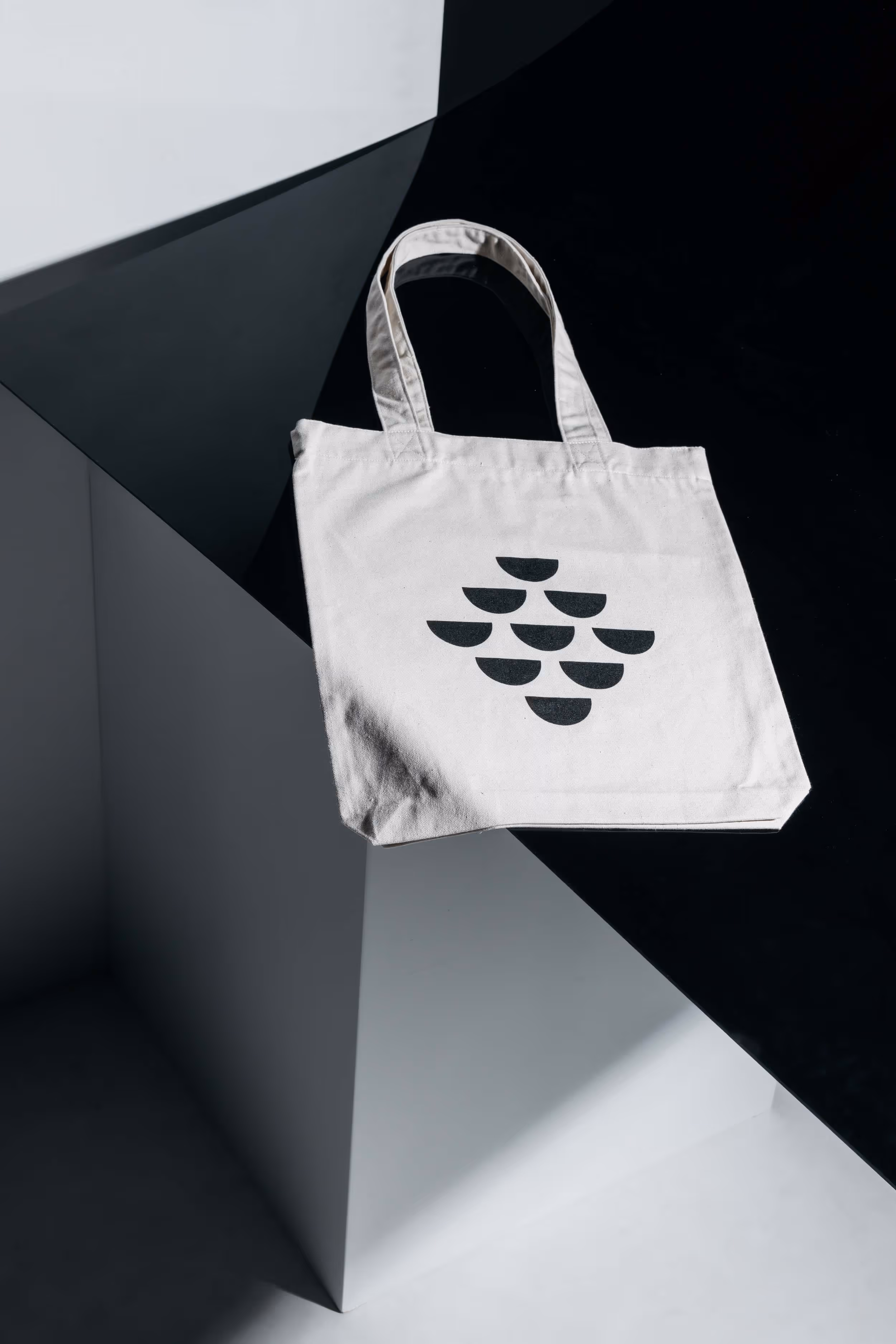Eine mit dem Logo bedruckte Stofftasche des Modelabels kienast, liegend auf einer schwarzen Kunststoffplatte