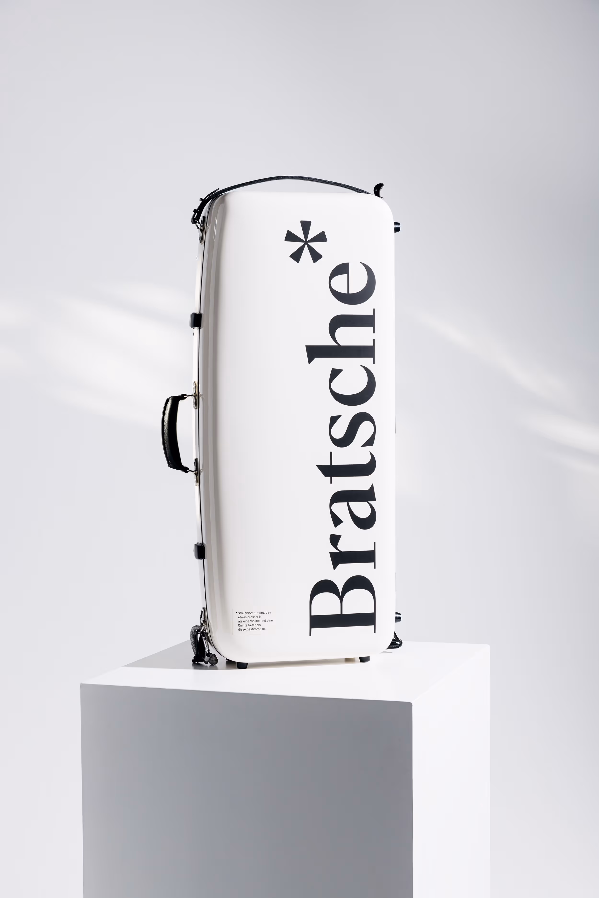 Weisser Instrumentkasten aus Kunststoff, beklebt mit schwarzer Typografie, stehend auf weissem Kubus und vor weissem Hintergrund