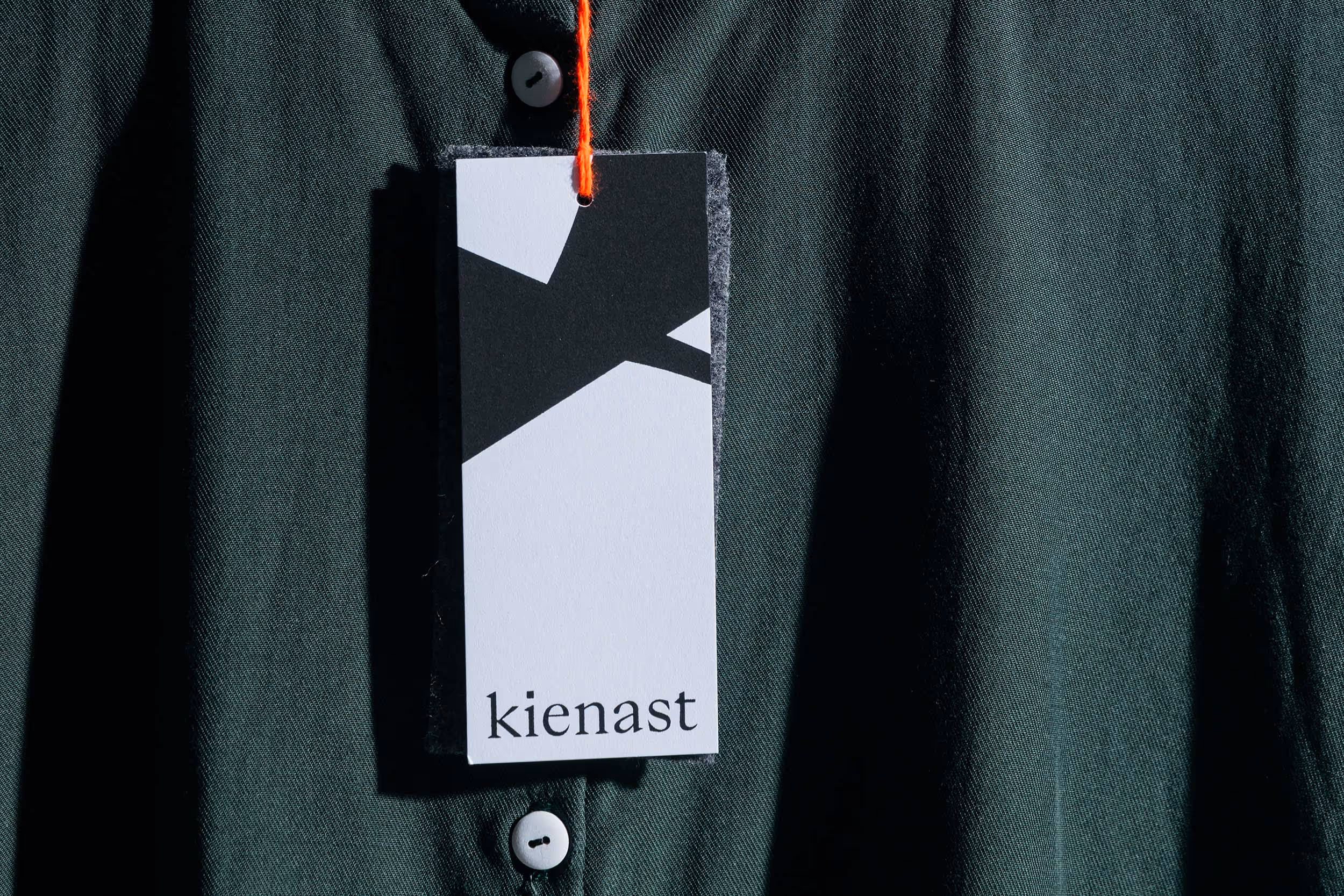 Detailsansicht eines an einem Kleidungsstück hängenden Tags für das Modelabel kienast