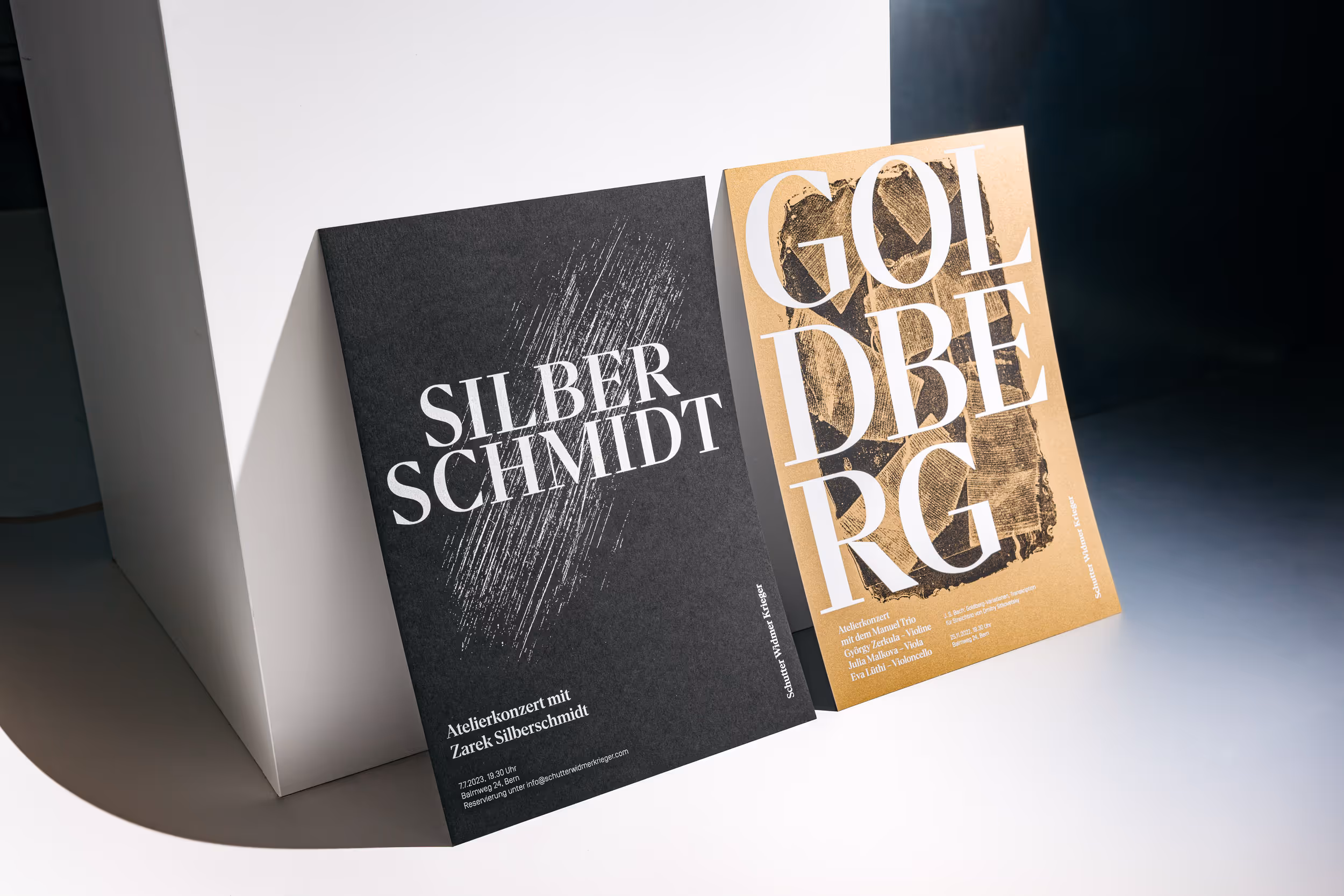 Schwarzes und goldenes Konzertplakat für das Geigenbauatelier Schutter Widmer, angelehnt an weissen Kubus