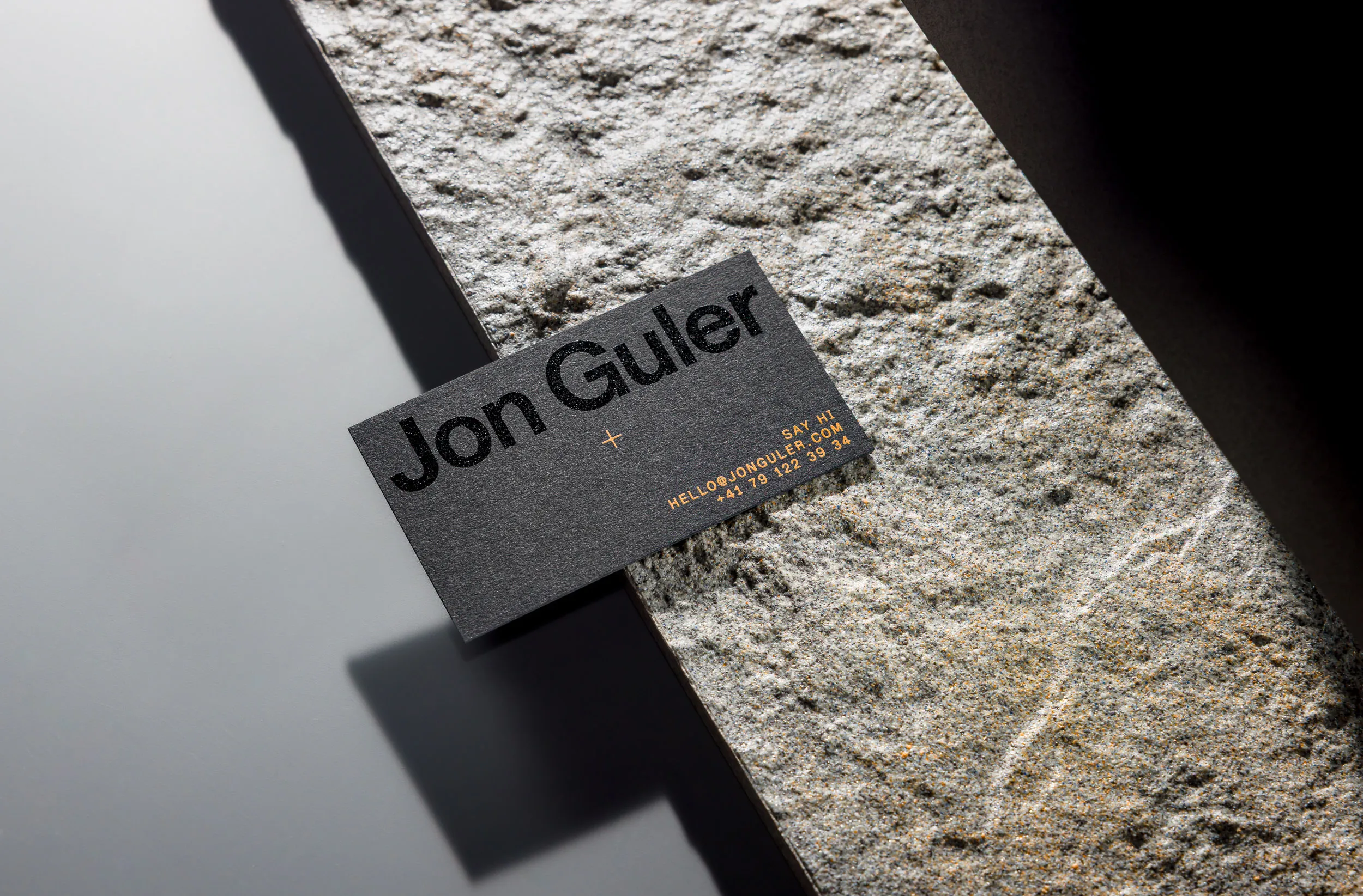 Vorderseite der Schwarz auf schwarzes Papier gedruckten Visitenkarte für Jon Guler, liegend auf einer Steinplatte