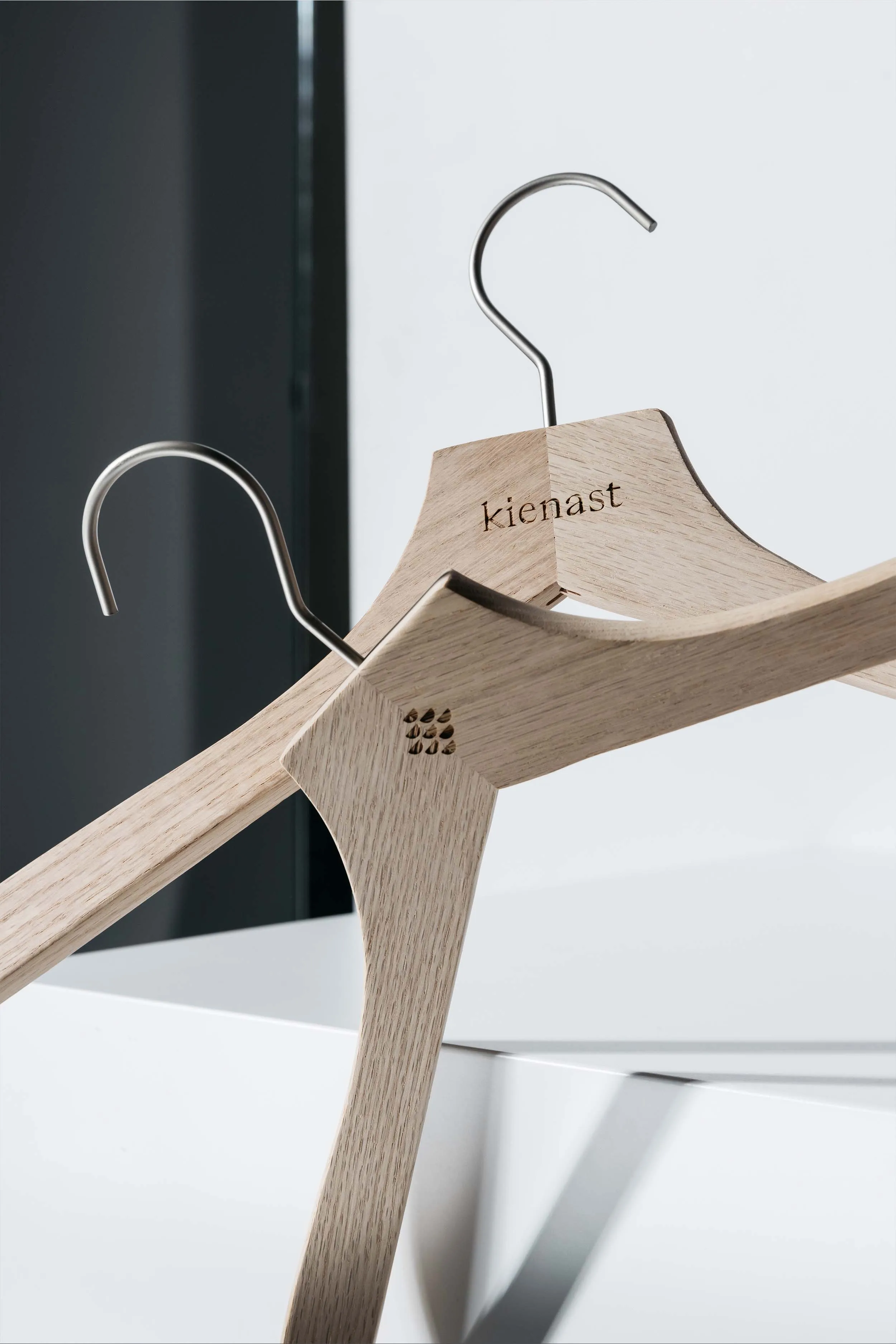 Zwei Holzkleiderbügel mit eingefrästem Logo des Modelabels kienast