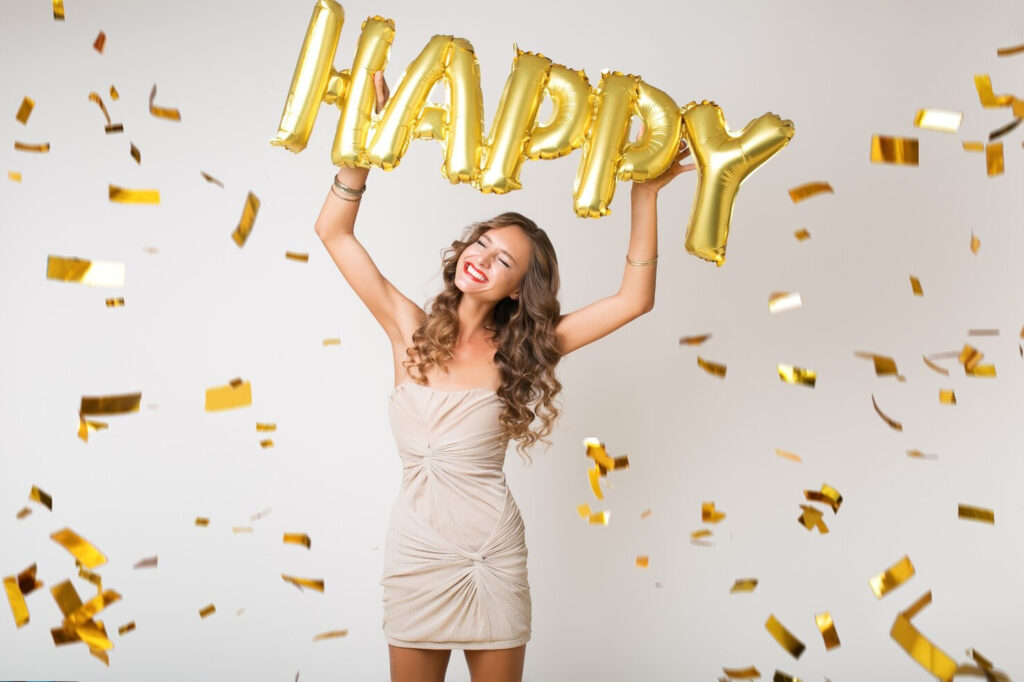 Woman in a dress holding up happy balloon for anniversary