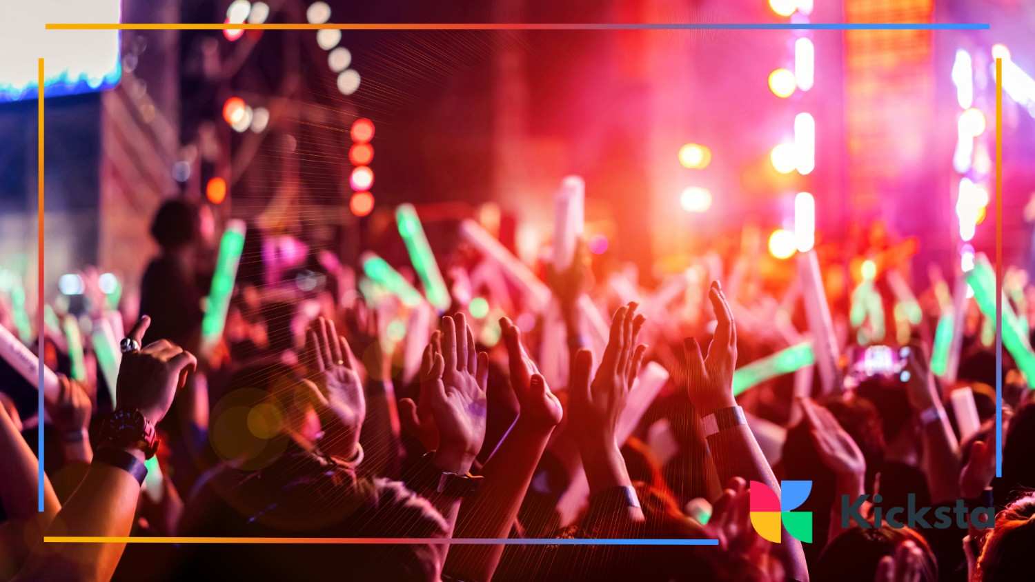 Crowd raising hands at a vibrant music concert with neon lights and glowing sticks in the air