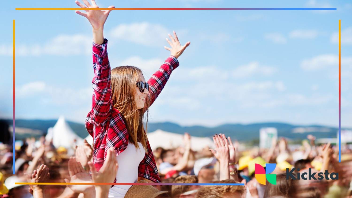 Excited festival-goer on someone’s shoulders with arms raised, enjoying a concert in an open-air venue