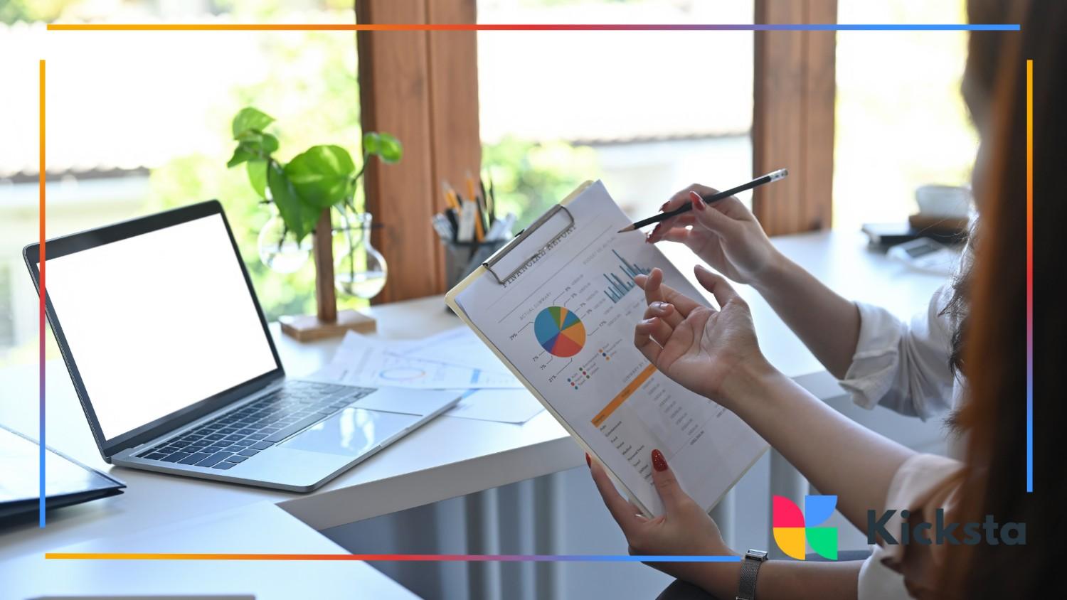 Two people review colorful charts and performance data in a bright, modern office