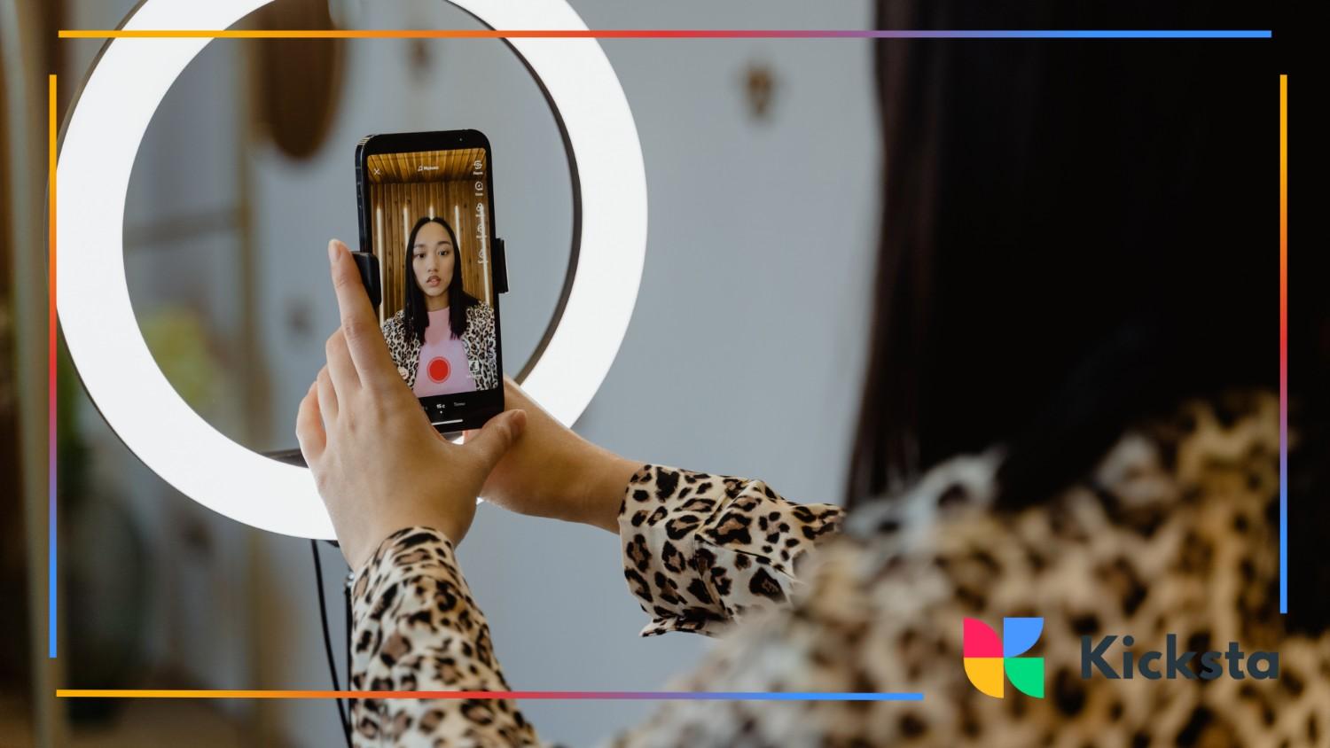 A fashion-forward creator films herself using a smartphone and ring light — representing influencer collaborations, premium beauty campaigns, or luxury product promos in high-end digital marketing.