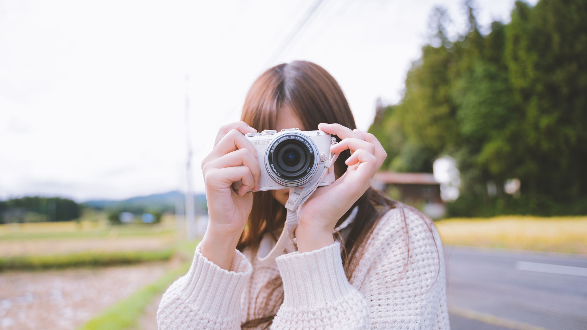 Photographer reviewing camera next to laptop displaying Instagram feed, symbolizing content creation, social media marketing, and digital photography workflow.